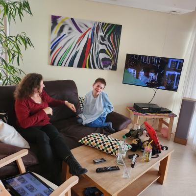 Schüler Sitzt rechts auf dem braunen Sofa, links sitzt eine Betreuerin und schaut nach ihm