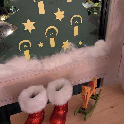 Weihnachtsdekoration steht am Fenster, ein paar weihnachtsmannschuhe und ein kleines Schaukelpferd