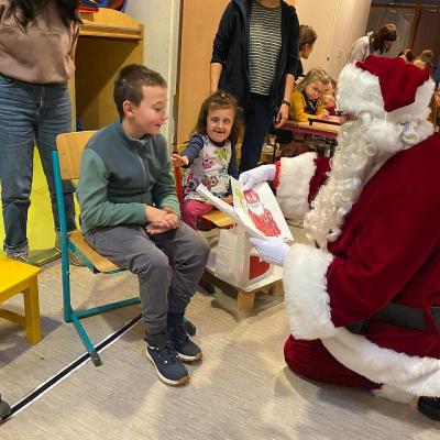 Ein Weihnachtsmann bekommt ein gemaltes Bild von sich selbst von einem Schüler überreicht.