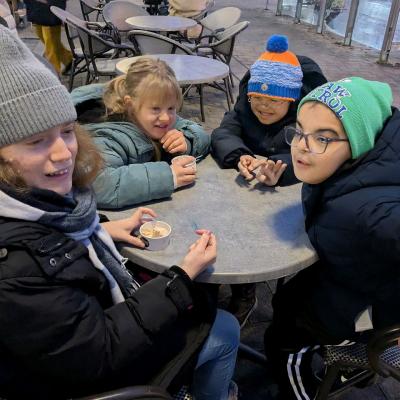 4 Kinder sitzen am Tischen im Kreis und lachen 