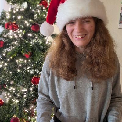 Ein Mädchen schaut lachend in die Kamera und hat eine Weihnachtsmütze auf