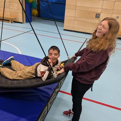 Ein Junge und ein Mädchen spielen an der Netzschaukel, haben Spaß lachen beide in die Kamera