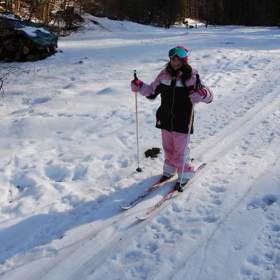 Sophia läuft in der Loipe und lächelt in die Kamera. Im Hintergrund sieht man Bäume und andere Schüler:innen im Schnee.