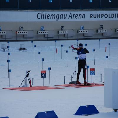 Am Schießstand steht ein Biathlet und hat sein Gewehr im Anschlag. Sein Trikot hat die Nummer 7.
