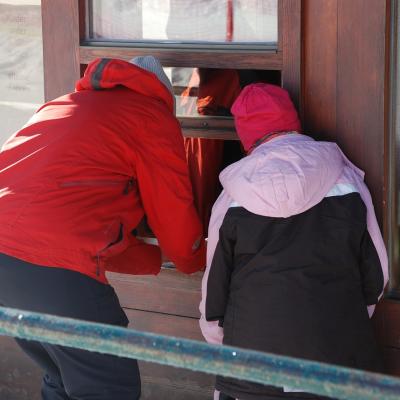 Frau Gauch und Sophia beugen sich in ein Fenster, um die Tickets für das Snowtubing zu kaufen.