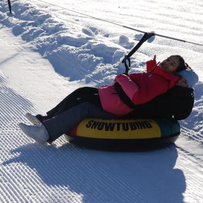 Ghofran liegt auf Lenas Schoß in einem Reifen, der mit einem Seil vom Lift gezogen wird. Beide lächeln in die Kamera.