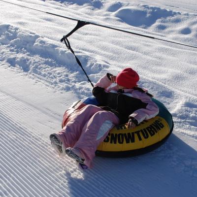 Sophia sitzt ganz entspannt in einem Reifen, der mit einem Seil vom Lift gezogen wird.