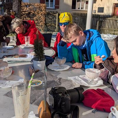 Ghofran, (dahinter nicht zu erkennen Marija), Frau Fecke, Frau Gauch, Maik, Luca und Sophia sitzen am Tisch und essen Eis bzw. trinken ihr Getränk.