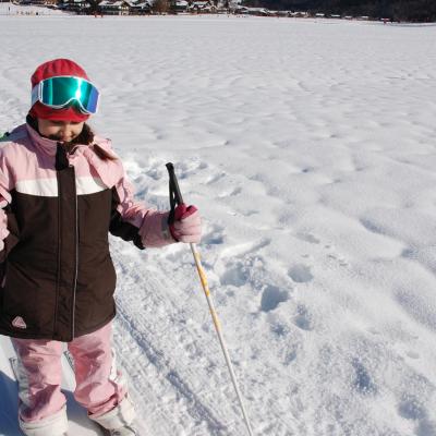 Sophia läuft in der Loipe mit Stöcken in den Händen. Neben ihr sieht man schneebedeckten Boden.