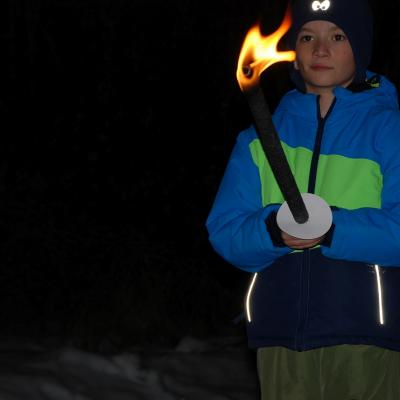 Luca hält eine brennende Fackel mit beiden Händen. Um ihn herum ist es Nacht.