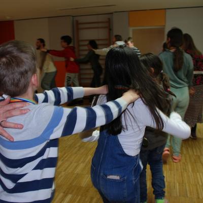Luca, Ghofran und Sophia sind von hinten zu sehen, wie sie in einer Menschenschlange Polognese laufen.