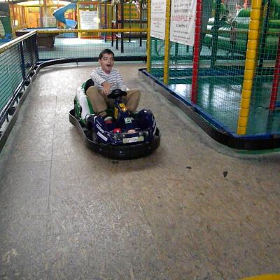 Ein Junge fäht mit einem kleinen Go Cart und lacht dabei. 