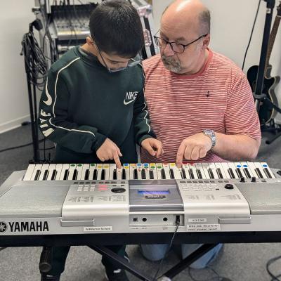 Ein mann und ein Junge üben/spielen am Keyboard 