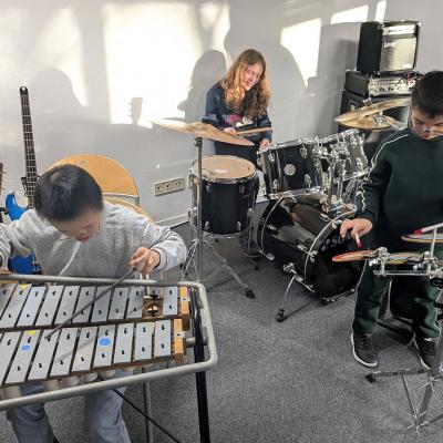 Eine Junge spiel ein Glockenspiel, ein Mädchen am Keyboard, ein Junge am kleinen Schlagzeug