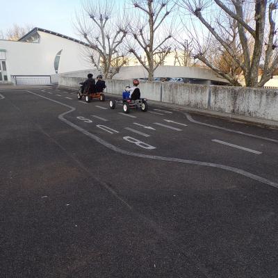 Zwei Kettcars mit Kindern fahren über den großen Verkehrsübungsplatz.