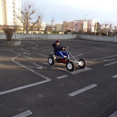 Zwei Kettcars mit Kindern fahren auf einem Übungsplatz