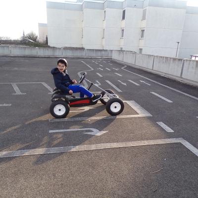 Ein Junge sitz im Kettcar lacht und hat Spaß beim fahren.