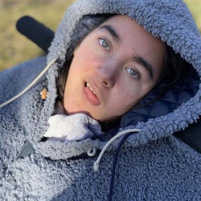 Eine junge Frau im Rollstuhl lächelt in die Kamera