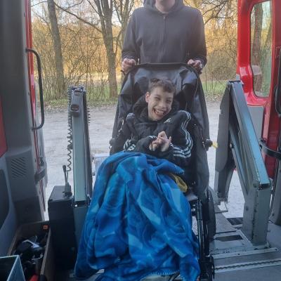 Ein Mann und ein Junge stehen in einem Auto. Der Junge sitzt im Buggy und lacht. 