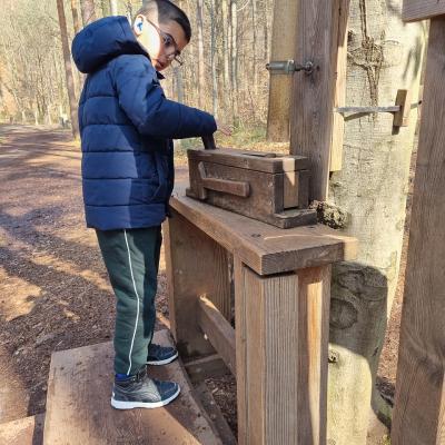 Ein Junge steht vor eine großen Murmelbahn aus Holz und bedient dort eine Vorrichtung. 