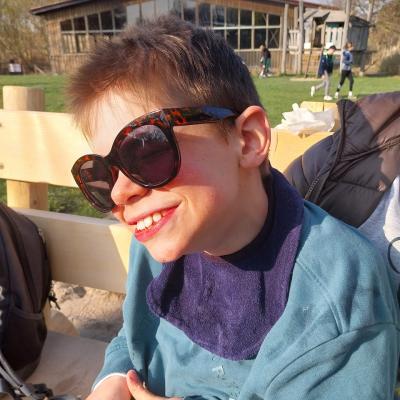 Schüler hat eine Sonnenbrille auf, lacht in die Sonne hinein