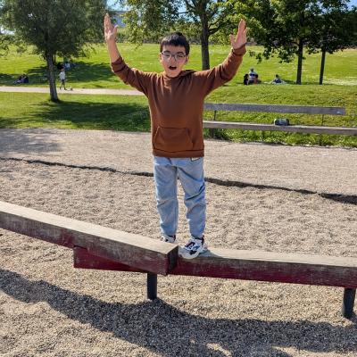 Ein Junge balanciert auf einem Balken und freut sich