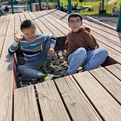 zwei Jungs sitzen auf dem Klettergerüst und lachen in die Kamera