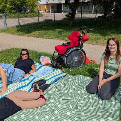 2 Frauen und ein Mädchen genießen die Sonne auf einer Decke