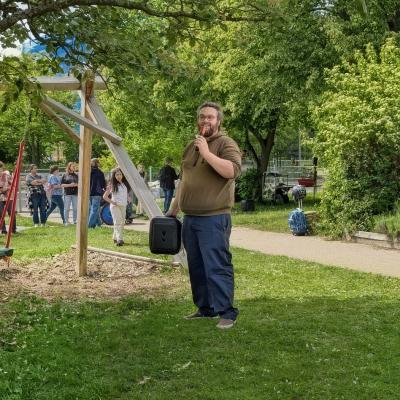 Ein Mann halt ein Mikrofon und spricht an die Gäste