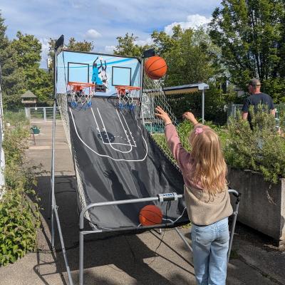 Ein Mädchen steht am Basketballkorb und wirf einen Ball