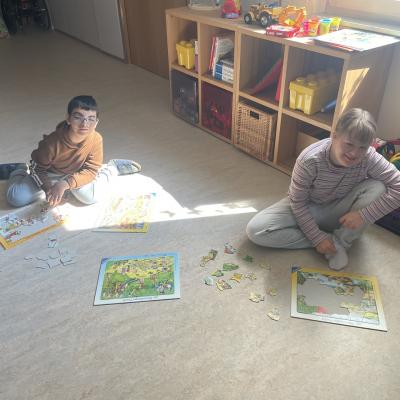 Eine junge Frau und ein Junge sitzen auf dem Boden und puzzeln.