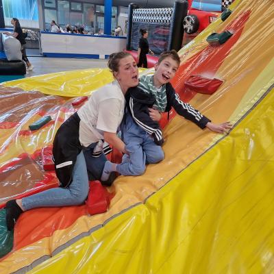 Eine Frau die einem Jungen dabei hilft, auf der Hüpfburg zu klettern.