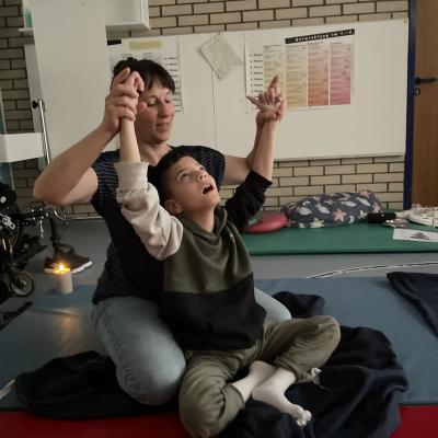 Ein Schüler macht gemeinsam mit einer Lehrerin die Yoga-Übung „Sonne”.