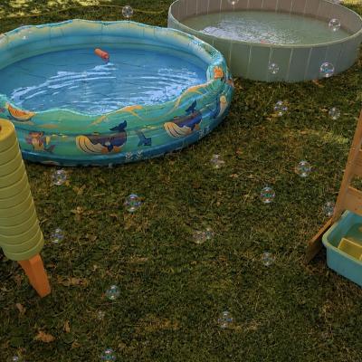Ein Plantschbecken mit Wasser gefüllt und ein Wasserspiel stehen auf der Wiese