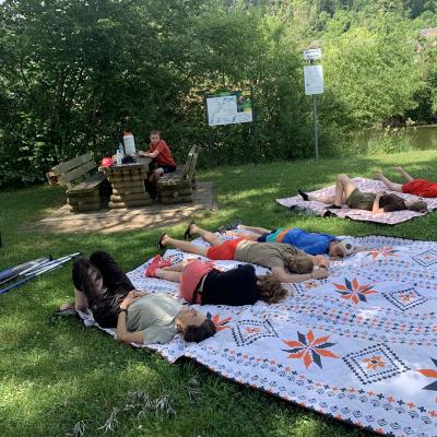 Nach der Kanutour ruhen sich die Teilnehmer im Schatten auf Picknickdecken aus.