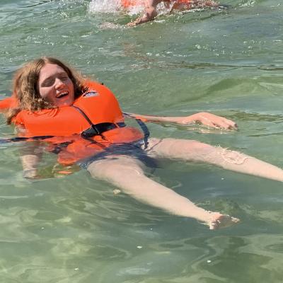 Eine Schülerin badet mit Schwimmweste im See.