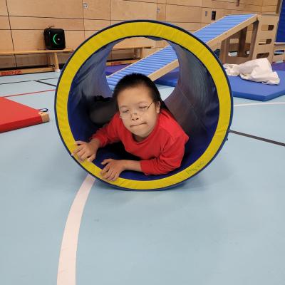 Ein Junge, der in der Sporthalle auf einem Trampolin hüpft. 